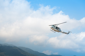 Fototapeta na wymiar Helicopter in flight, blue sky background
