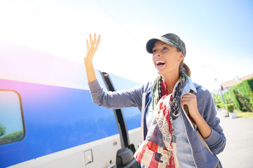 Young woman waving goodbye at passenger in train station