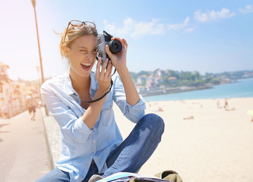 Cheerful girl taking pictures of the beach, tourist area