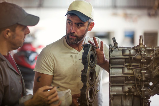 Two men repairing outboard motor in boat repair workshop
