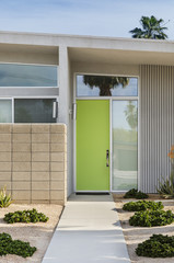Close up of a Lime green front door with drought resistance plants lining the entrance