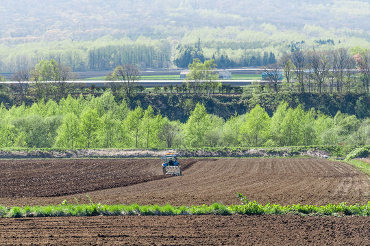 畑を耕すトラクター / 北海道の農業イメージ