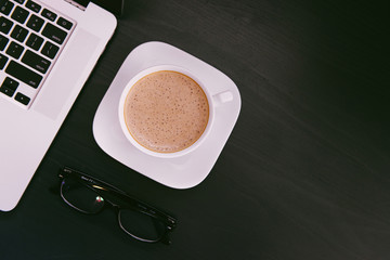 White cup of coffee on a black background.