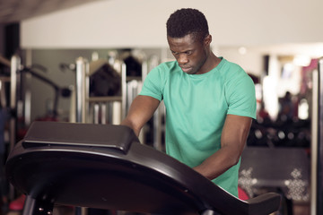 black man manipulates a running machine at the gym