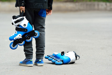 little beautiful boy with roller skates in his hands