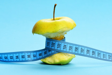 Apple bitten and tied with blue measuring tape