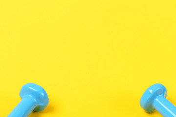 Tops of dumbbells in light blue color on yellow background