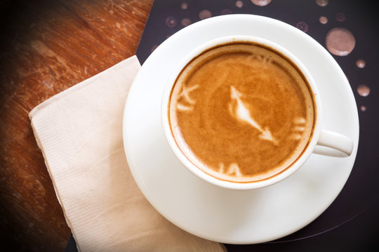 Hot coffee cup on wooden table. Top view. Latte art of Clock. Food and drink background.