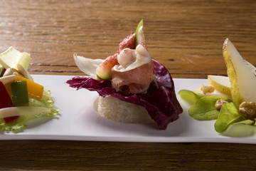 Entry dish with parma ham, fig, pear, purple lettuce and fresh grains