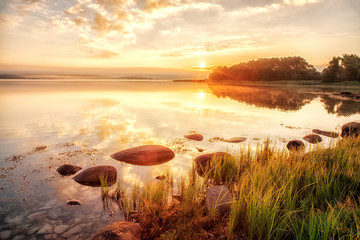 Sunrise scenery over Northern sea in Sweden, coast line with green grass an foreground, epic...