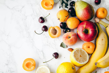 Summer fruits assorted on white marble background. Fresh raw food concept. Copy space