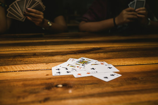 people is playing game of cards with king or queen or jack or ace or number on the wooden table. The game of slave card. 