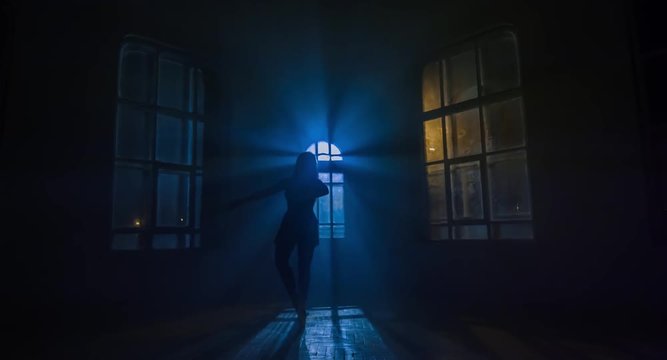 Graceful woman dances in moonlight penetrates through the window. Silhouette