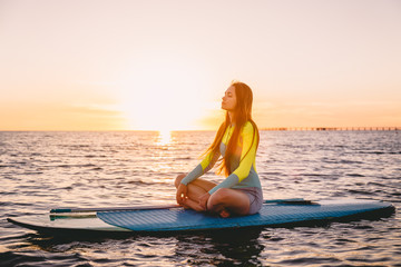 Fototapeta na wymiar Stand up paddle boarding on a quiet sea with warm sunset colors. Relaxing on ocean