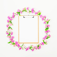 Round frame made of flowers and clipboard on white background. Flat lay, top view. Blogger or freelancer composition