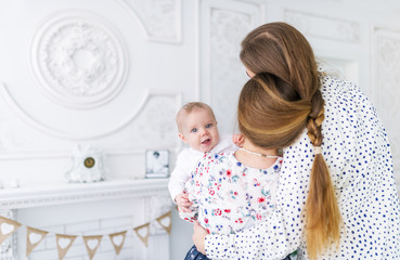 Baby boy in white pajamas looks over father's shoulder while mother embraces him