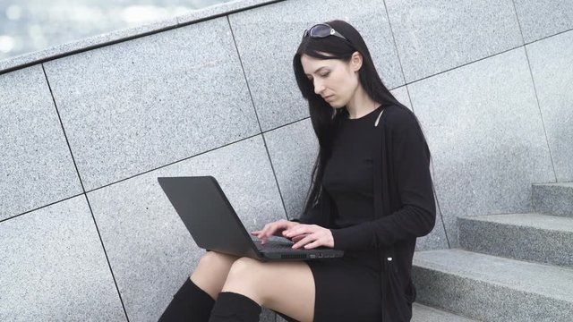 Attractive woman using a laptop, sitting on the steps 