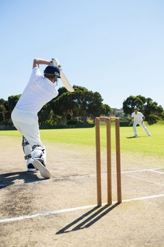 Rear view of cricket player batting while playing on field
