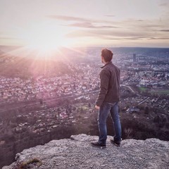 Man on a rock looking at a city