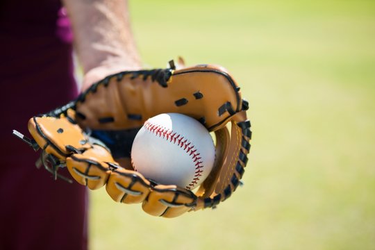 Cropped image of baseball pitcher holding ball on glove