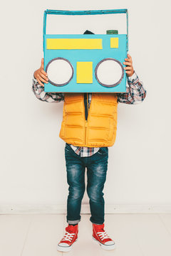 Little hipster boy hidding his face with diy colored radio