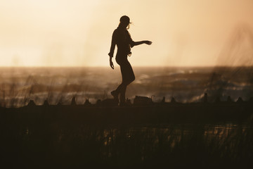 Young woman walking alone the California coast at sunset in San Francisco