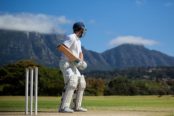 Full length of cricket player practicing against blue sky