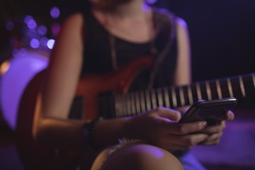Obraz na płótnie Canvas Mid section of female guitarist using mobile
