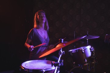 Fototapeta na wymiar Confident female drummer performing in nightclub