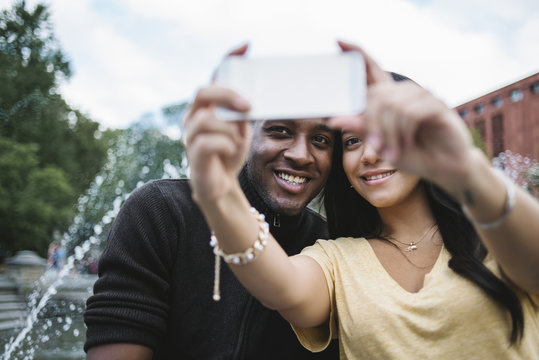 Black young couple taking a selfie in the city