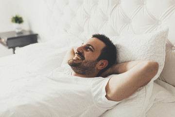 Young handsome man lying on the bed and laughing