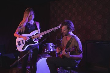 Obraz premium Man and woman performing with guitars in nightclub