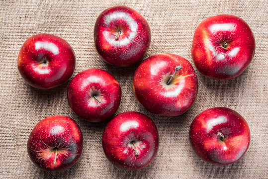 Top view of eight colorful bright shiny red apples on brown sacking material