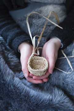 Girls hands holding tiny raffia basket - vertical