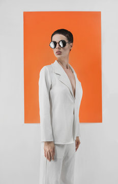 Fashionable model with sunglasses in front of white and orange background