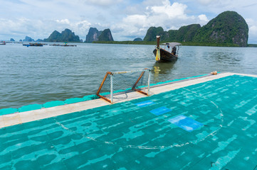 The small football field of Koh Panyee with long tail boat and karst in the background