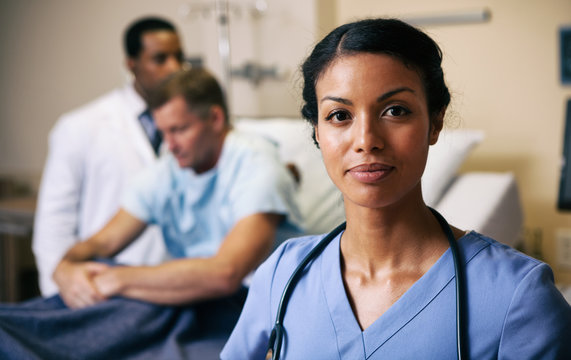 Hospital Confident Nurse With Doctor Checking Patient In Background