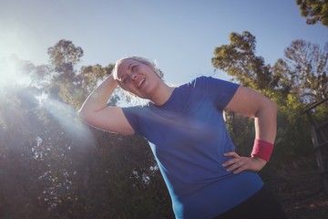 Tired woman standing with hand on hip in the boot camp