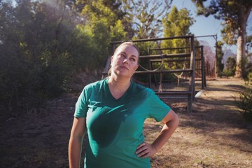 Tired woman standing with hand on hip in the boot camp