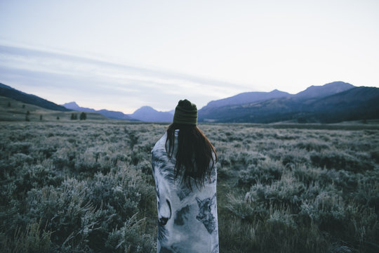 A girl staring out into a cold frosty field wrapped in a blanker