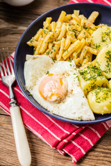 Fried egg served with potatoes and yellow beans.
