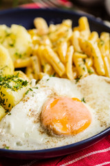 Fried egg served with potatoes and yellow beans.