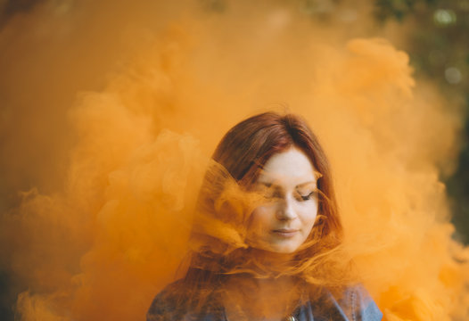 Woman immersed in a plume of orange smoke