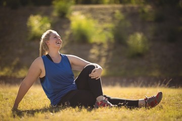 Happy woman relaxing on grass during obstacle course