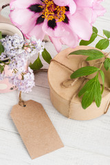 Fototapeta na wymiar Kraft gift box, peonies and lilac flowers