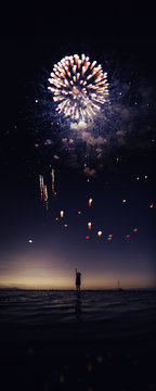 woman looking fireworks at sunset on the beach