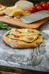 Mini pizza with asparagus. Traditional small pizza for personal eating filling with cheese, tomatoes and asparagus.