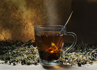 A cup of brewed herbal tea and dried thyme grass on kraft paper