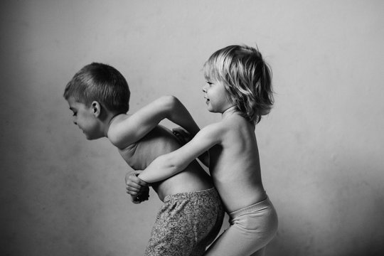 Black and white of two children playing together with their arms around each other