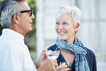 Senior couple talking enjoying cocktails at an outdoor party